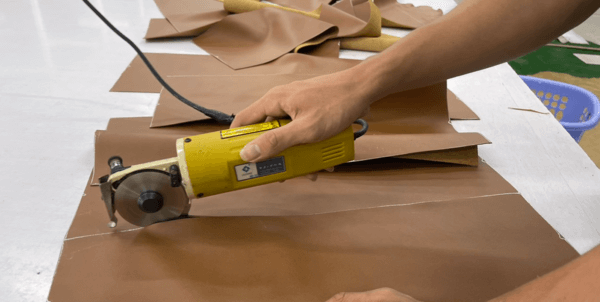 QA Furniture employee is handling the fabric cutting and upholstery assembly